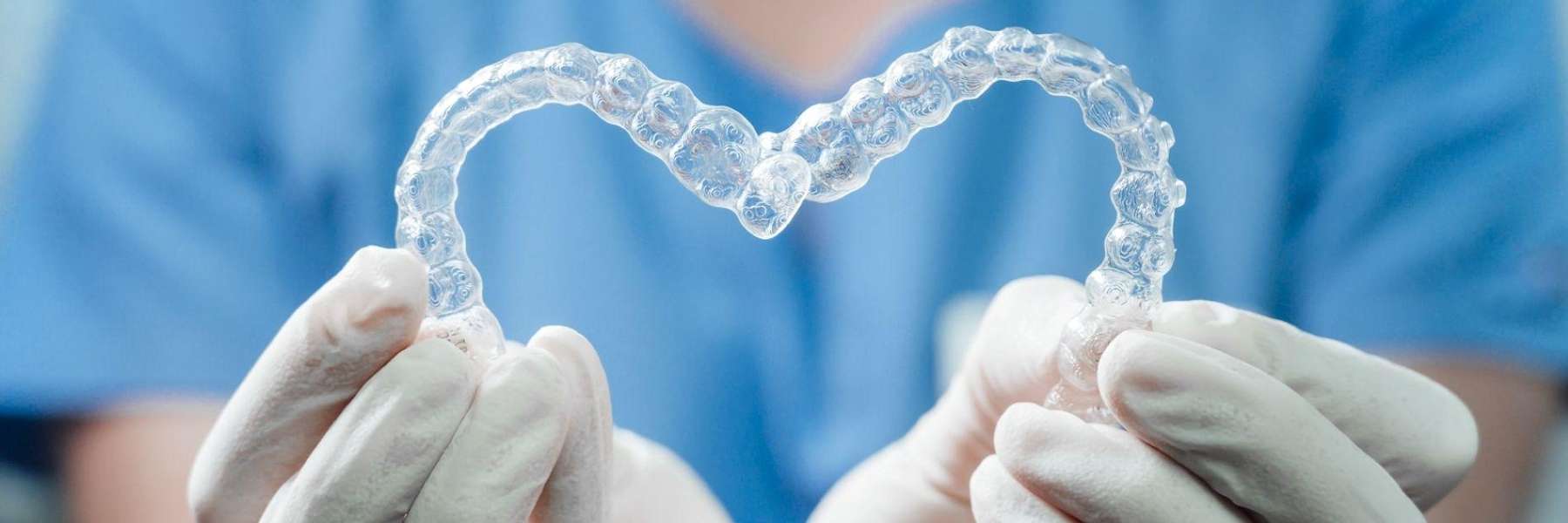 Dentist forming Invisalign aligners into a heart to show choices between Invisalign and clear braces