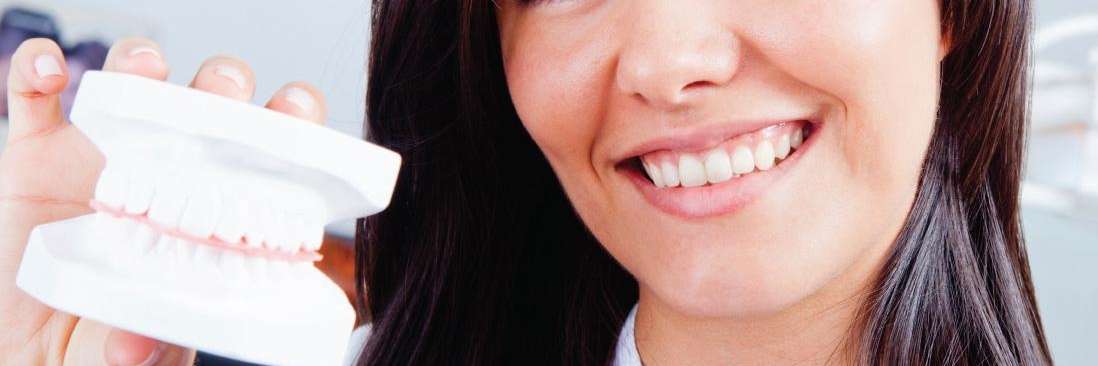 Lady smiling while holding dentures in Beachwood, Ohio